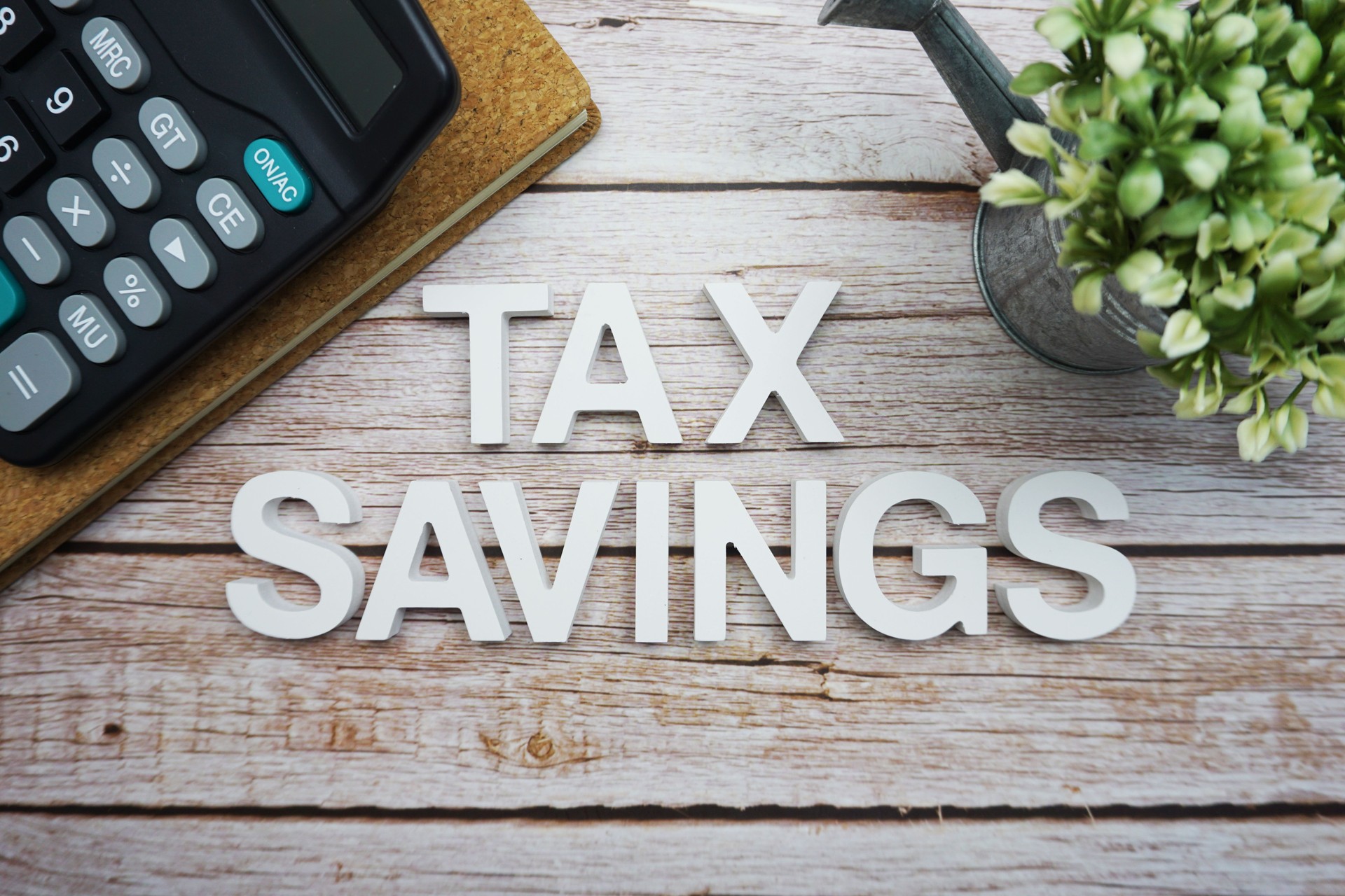 Tax Savings alphabet letters with calculator on wooden background